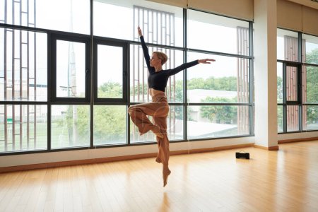 Téléchargez les photos : Talentueuse jeune femme dansant sur la musique dans un studio spacieux - en image libre de droit