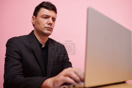 Téléchargez les photos : Un homme d'affaires fronçant les sourcils lisant sur un écran d'ordinateur portable et répondant à des e-mails - en image libre de droit