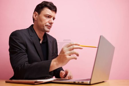 Foto de Empresario serio apuntando a la pantalla del ordenador portátil con lápiz al leer datos importantes o comparar números - Imagen libre de derechos