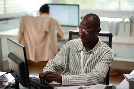 Téléchargez les photos : Homme d'affaires pensif en lunettes remplissant le document à son bureau - en image libre de droit