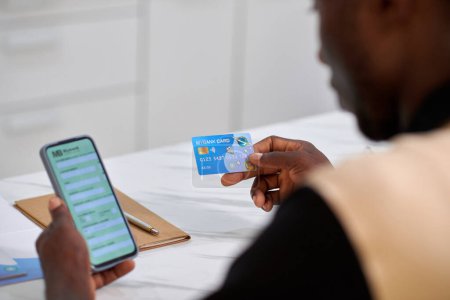 Téléchargez les photos : Homme entrant les données de carte de crédit sous forme bancaire sur smartphone, vue au-dessus de l'épaule - en image libre de droit