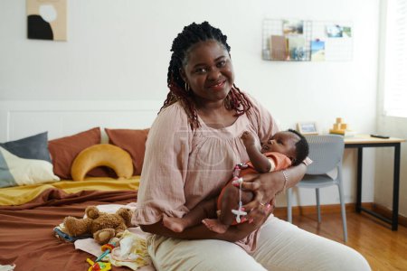 Téléchargez les photos : Portrait de femme noire heureuse berçant bébé pour dormir - en image libre de droit