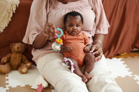 Téléchargez les photos : Image recadrée de la mère assise sur le sol et jouant avec bébé fille - en image libre de droit
