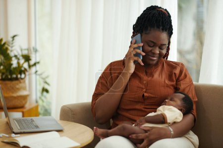 Photo for Portrait of Black woman sitting with baby on laps and taking on phone - Royalty Free Image