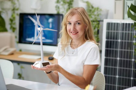 Téléchargez les photos : Portrait de femme souriante tenant un modèle de petite éolienne - en image libre de droit