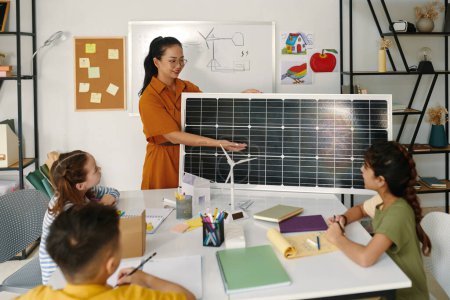 Foto de Profesor positivo mostrando a los niños el panel solar y explicando cómo funciona - Imagen libre de derechos