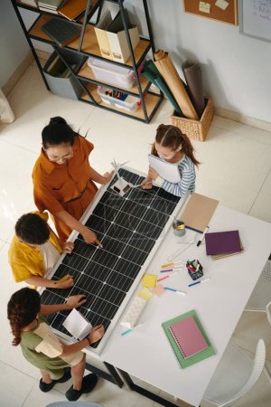 Téléchargez les photos : Enseignant expliquant aux enfants comment fonctionnent les cellules du panneau solaire, vue de dessus - en image libre de droit