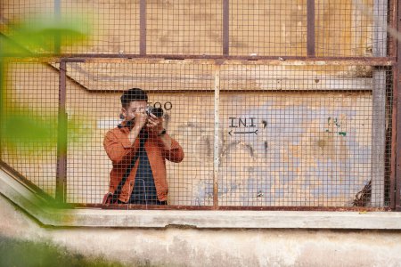 Téléchargez les photos : Journaliste photographiant des bâtiments abandonnés dans la vieille ville pour article de presse - en image libre de droit