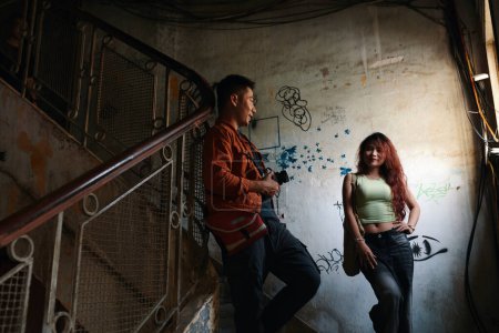 Téléchargez les photos : Jeune homme photographiant petite amie à l'intérieur bâtiment minable - en image libre de droit