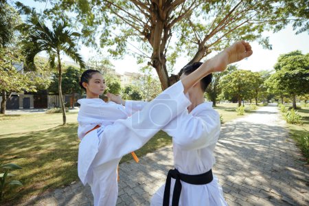 Téléchargez les photos : Jeune couple participant à la formation de combat taekwondo en plein air - en image libre de droit