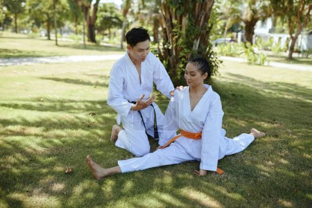Téléchargez les photos : Professeur de taekwondo remonter le moral fille faire splits wo échauffer avant la formation - en image libre de droit