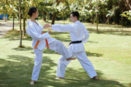 Photo for Girl with orange belt defending when fighting with black belt taekwondo athlete - Royalty Free Image