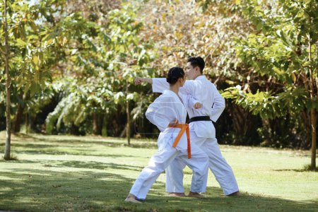 Photo for Black belt taekwondo athlete teaching girlfriend defense techniques - Royalty Free Image