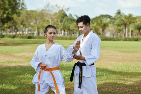 Photo for Instructor explaining female athlete how to position arms when doing taekwondo stance - Royalty Free Image