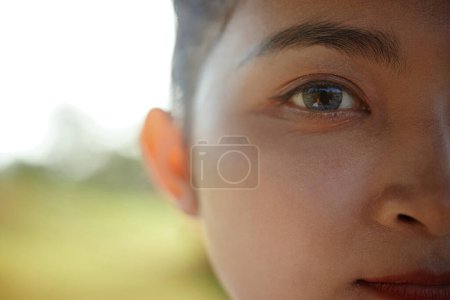 Photo for Half face of young female Asian taekwondo athlete with grey eyes standing outdoors - Royalty Free Image