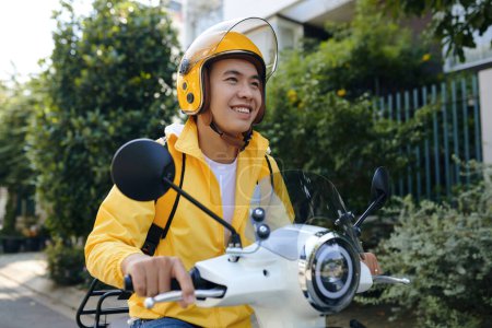 Foto de Smiling Vietnamese delivery man riding scooter - Imagen libre de derechos