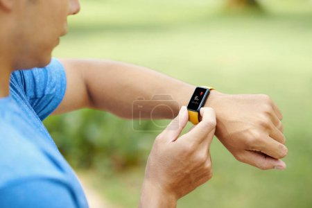 Téléchargez les photos : Image rapprochée du jogger vérifiant la fréquence cardiaque sur le moniteur de fitness - en image libre de droit