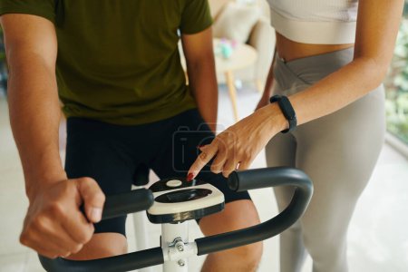 Photo for Closeup image of fit woman showing boyfriend how to set endurance on exercise bike - Royalty Free Image