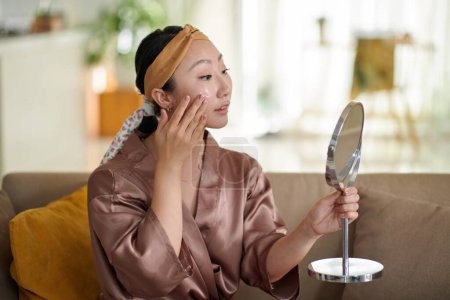 Photo for Portrait of smiling Chinese young woman applying brightening moisturizer - Royalty Free Image