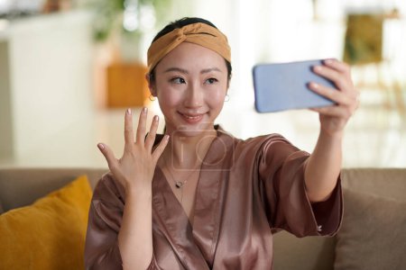 Téléchargez les photos : Heureuse femme chinoise montrant la manucure qu'elle a faite en prenant selfie - en image libre de droit