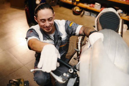 Foto de Reparador sonriente comprobando el apalancamiento de la motocicleta - Imagen libre de derechos