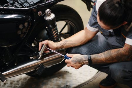 Foto de Trabajador de garaje reparación de motocicleta del cliente - Imagen libre de derechos