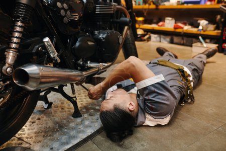 Foto de Trabajador de garaje que fija la parte inferior de la motocicleta - Imagen libre de derechos