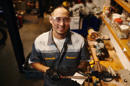 Photo for Portrait of smiling mechanic in goggles holding raspfile - Royalty Free Image