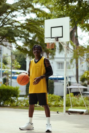 Photo for Cheerful young man playing streetball alone when waiting for friend - Royalty Free Image