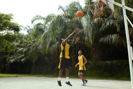 Photo for Black men playing game of streetball on outdoor court - Royalty Free Image
