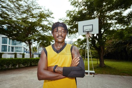 Téléchargez les photos : Portrait du joueur de streetball avec manchon de compression debout sur le court extérieur - en image libre de droit