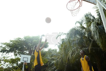 Photo for Sportsman throwing ball in basket when playing alone outdoors - Royalty Free Image