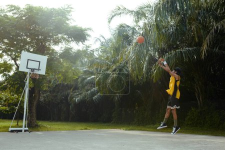 Photo for Sportsman shooting ball in basket when training on outdoor court - Royalty Free Image