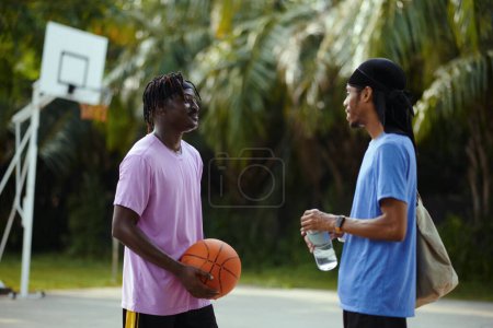 Smiling Black men talking on outdoor streetball court