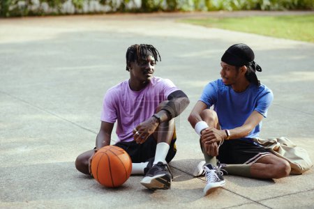 Fröhliche schwarze Freunde hängen nach dem Streetball zusammen