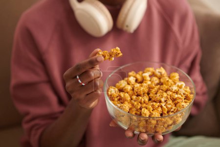 Zugeschnittenes Bild eines Mädchens, das Popcorn isst, wenn es einen Film zu Hause anschaut