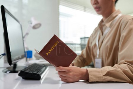 Téléchargez les photos : Gestionnaire de banque saisissant les données du passeport sur le client dans le formulaire sur l'écran de l'ordinateur - en image libre de droit