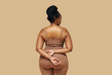 Studioporträt einer kurvigen Schwarzen in Sportbekleidung, Blick von hinten