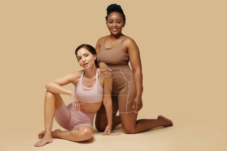 Téléchargez les photos : Portrait studio de joyeuses femmes noires et caucasiennes en shapewear - en image libre de droit