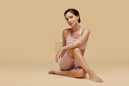 Foto de Mujer Slim fit en ropa deportiva sentada en el piso del estudio - Imagen libre de derechos