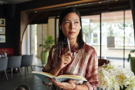 Porträt einer nachdenklichen Geschäftsfrau mit Planer in ihrem Restaurant