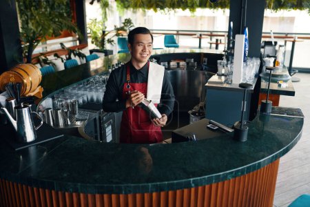 Foto de Cantinero sonriente haciendo cóctel en el mostrador del bar - Imagen libre de derechos