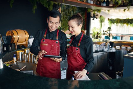 Smiling bartenders checking orders on tablet computer