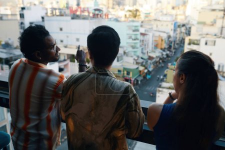 Téléchargez les photos : Groupe de personnes debout sur le balcon et regardant la ville animée, vue de l'arrière - en image libre de droit