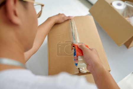 Volunteer sealing cardboard box with food and necessities
