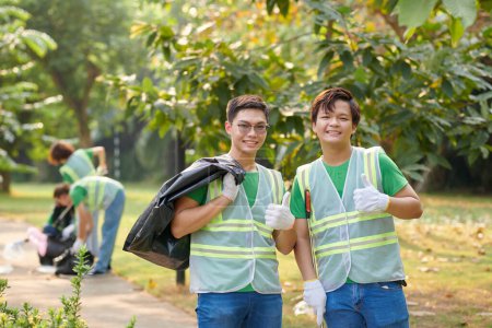 Foto de Voluntarios sonrientes con bolsas de basura mostrando los pulgares hacia arriba - Imagen libre de derechos