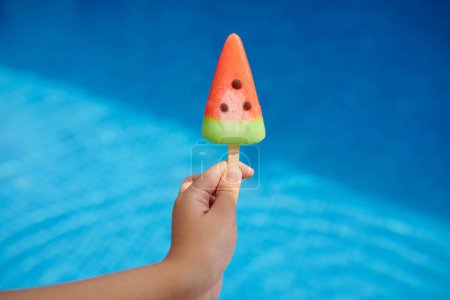 Téléchargez les photos : Fille tenant crème glacée pastèque contre la piscine - en image libre de droit