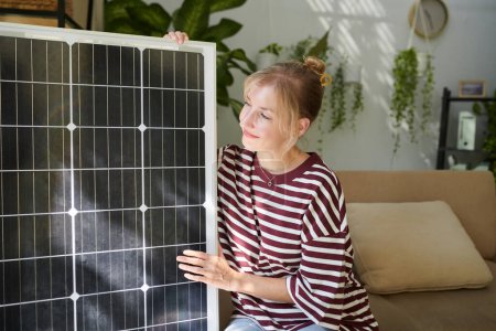 Foto de Mujer feliz mirando el panel solar entregado a su casa - Imagen libre de derechos