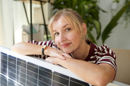 Photo for Portrait of woman leaning on solar panel and smiling at camera - Royalty Free Image