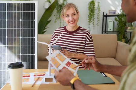Photo for Smiling woman listening to manager explaining benefits of solar panel system - Royalty Free Image